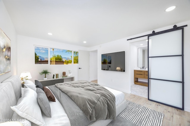 bedroom with a barn door and light hardwood / wood-style flooring