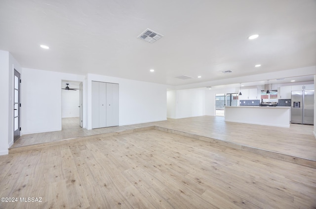 unfurnished living room featuring ceiling fan and light hardwood / wood-style floors