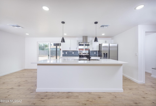 kitchen with extractor fan, stainless steel fridge, white cabinetry, and an island with sink