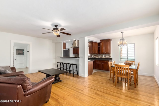 living room featuring ceiling fan with notable chandelier and light hardwood / wood-style flooring