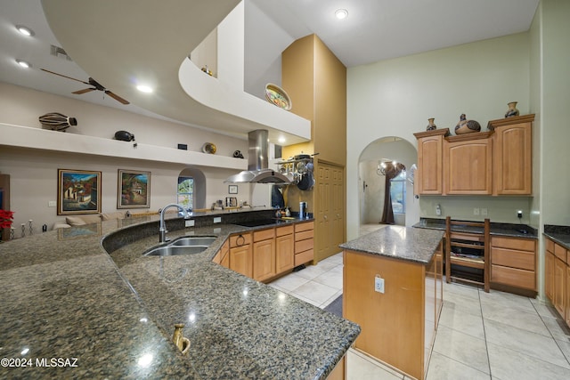 kitchen featuring island exhaust hood, ceiling fan, sink, a high ceiling, and a center island