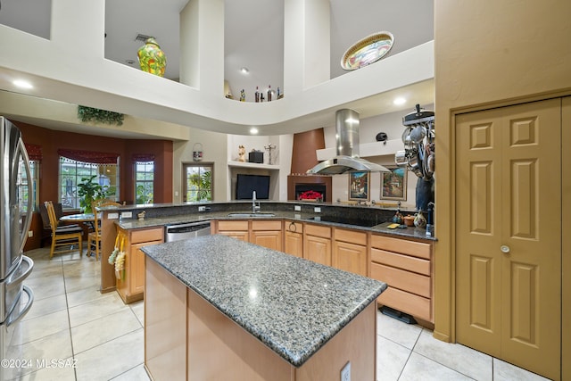 kitchen with a center island, sink, a towering ceiling, light tile patterned floors, and island exhaust hood