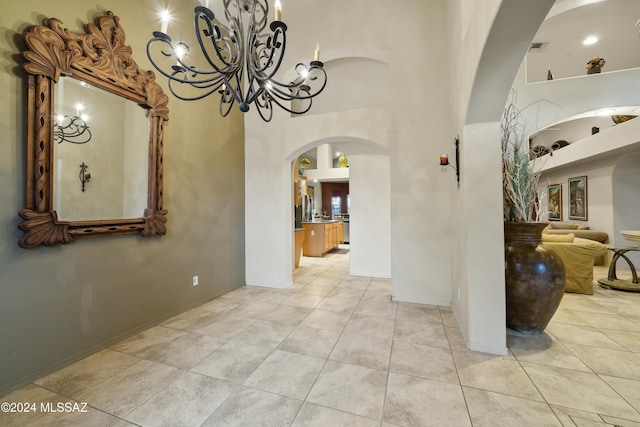 interior space with a notable chandelier, a towering ceiling, and light tile patterned floors