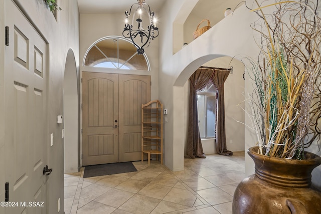 tiled foyer entrance featuring a towering ceiling and an inviting chandelier