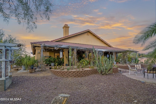 back house at dusk featuring a patio