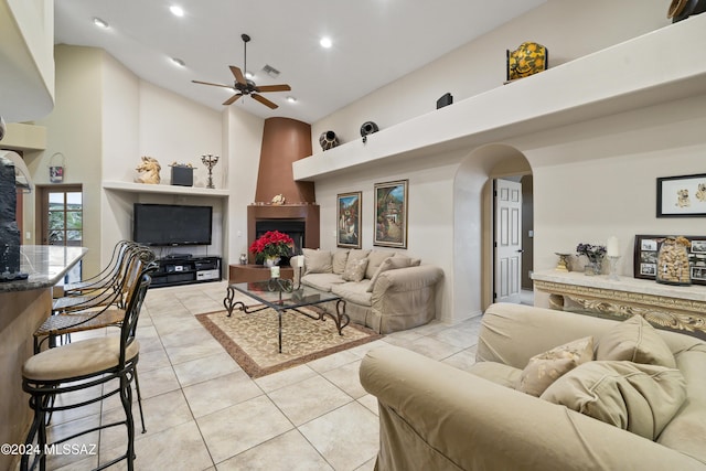 living room featuring a fireplace, a high ceiling, ceiling fan, and light tile patterned flooring