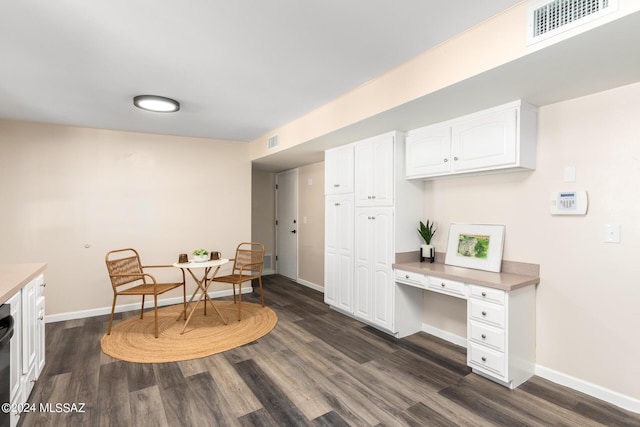 dining room with dark hardwood / wood-style flooring and built in desk