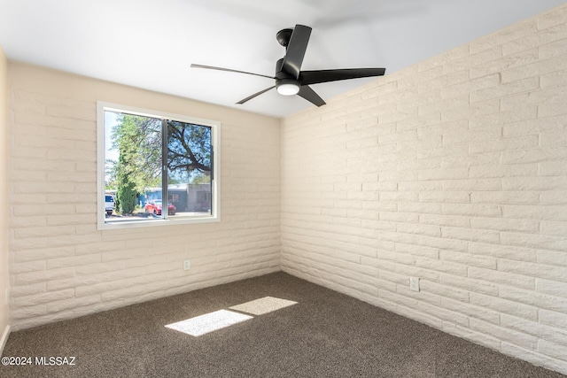 unfurnished room with carpet flooring, ceiling fan, and brick wall