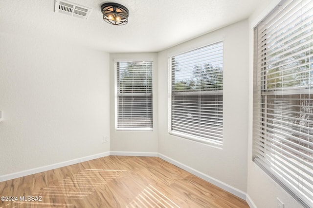 unfurnished room with a textured ceiling and light hardwood / wood-style floors