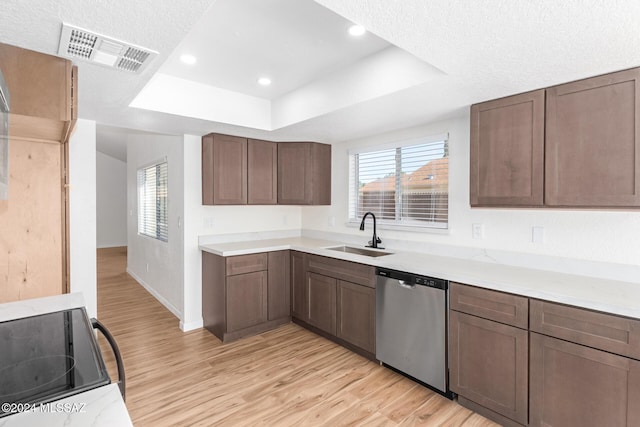 kitchen with light wood-type flooring, stainless steel dishwasher, a textured ceiling, a tray ceiling, and sink