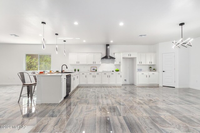 kitchen with pendant lighting, white cabinetry, wall chimney range hood, and sink