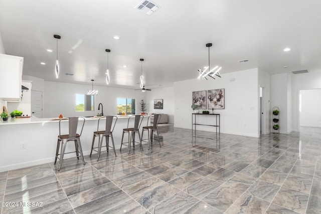 kitchen featuring white cabinetry, hanging light fixtures, a breakfast bar area, and ceiling fan