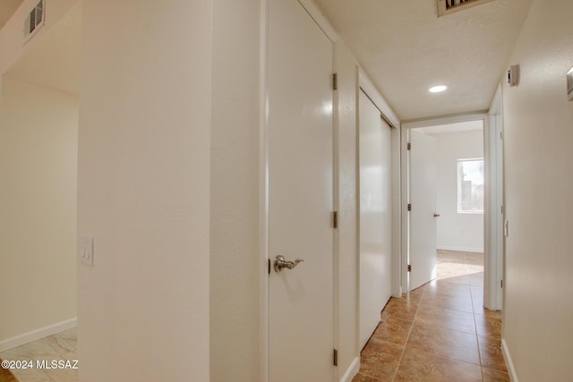 hall featuring light tile patterned floors and a textured ceiling