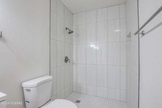 bathroom featuring toilet and a tile shower