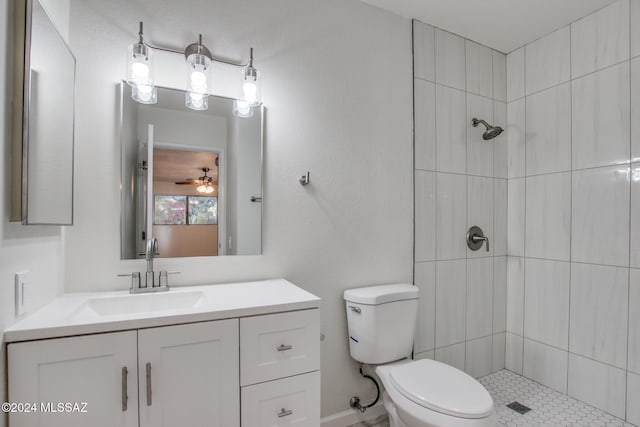 bathroom featuring tiled shower, vanity, toilet, and ceiling fan