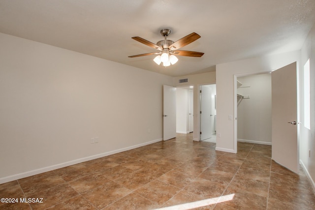 unfurnished bedroom featuring a walk in closet, ceiling fan, and a closet