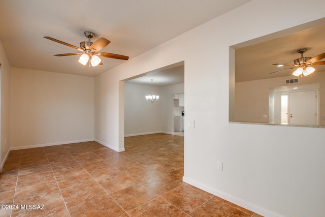 spare room featuring tile patterned flooring and ceiling fan with notable chandelier