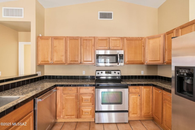 kitchen with light tile patterned floors, appliances with stainless steel finishes, and high vaulted ceiling