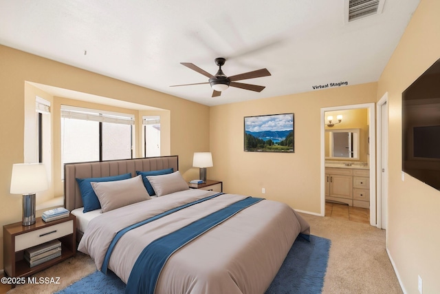 carpeted bedroom with ensuite bath and ceiling fan