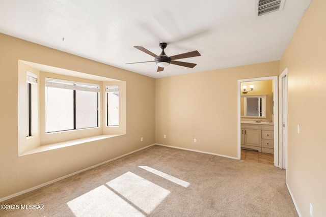 unfurnished bedroom featuring ceiling fan, light carpet, and ensuite bathroom