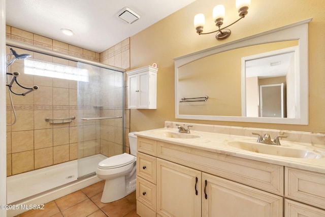 bathroom featuring toilet, vanity, tile patterned flooring, and a shower with door