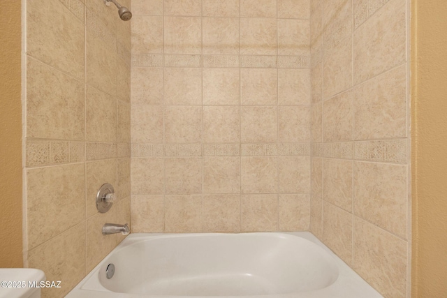 bathroom with toilet and tiled shower / bath combo