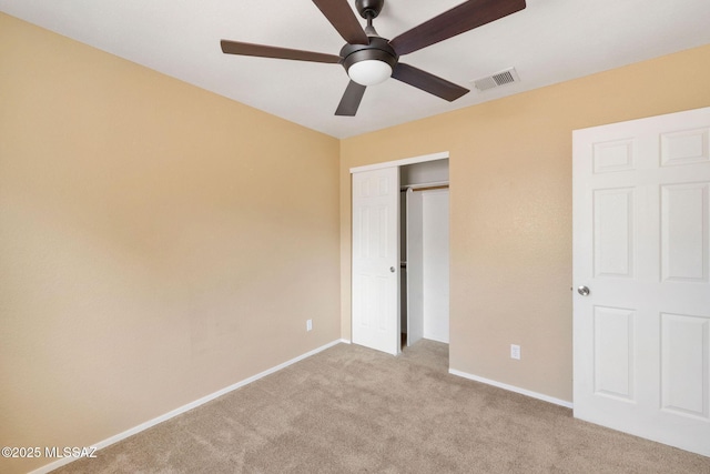 unfurnished bedroom with ceiling fan, light colored carpet, and a closet