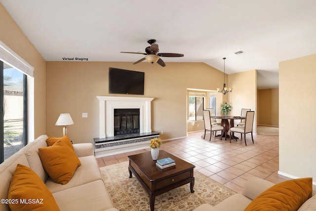 living room with lofted ceiling, light tile patterned flooring, and ceiling fan with notable chandelier