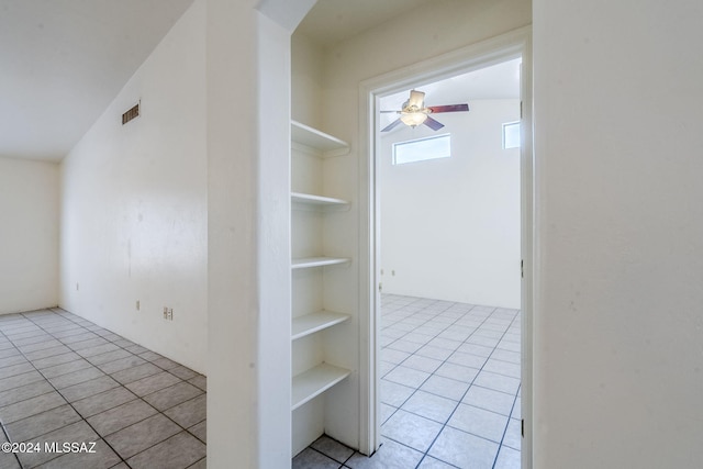 corridor with light tile patterned floors, built in features, and lofted ceiling