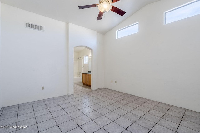 unfurnished room featuring arched walkways, visible vents, light tile patterned flooring, vaulted ceiling, and ceiling fan