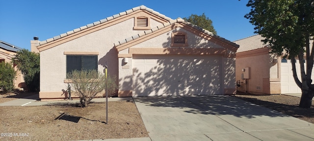 view of front of house with a garage, driveway, a tile roof, and stucco siding