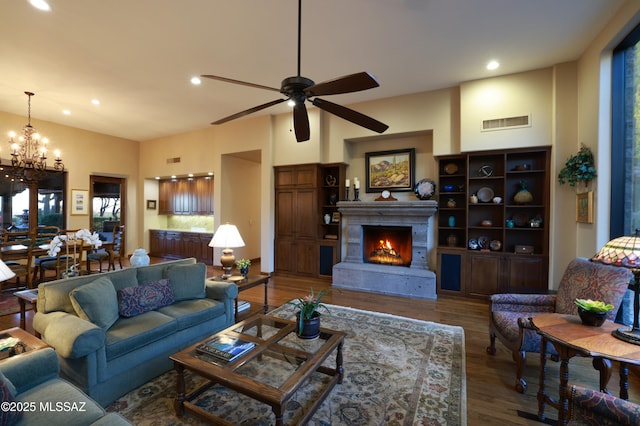 living room with ceiling fan with notable chandelier and dark wood-type flooring