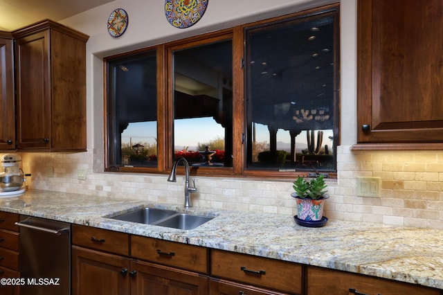 kitchen with light stone countertops, backsplash, and sink