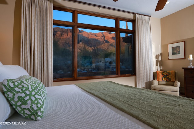 bedroom with ceiling fan and a mountain view