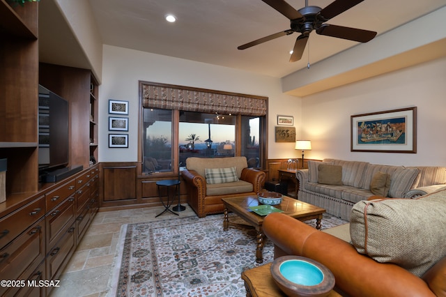 living room featuring ceiling fan and wooden walls