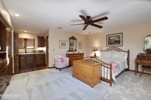 bedroom with sink, connected bathroom, ceiling fan, and light colored carpet