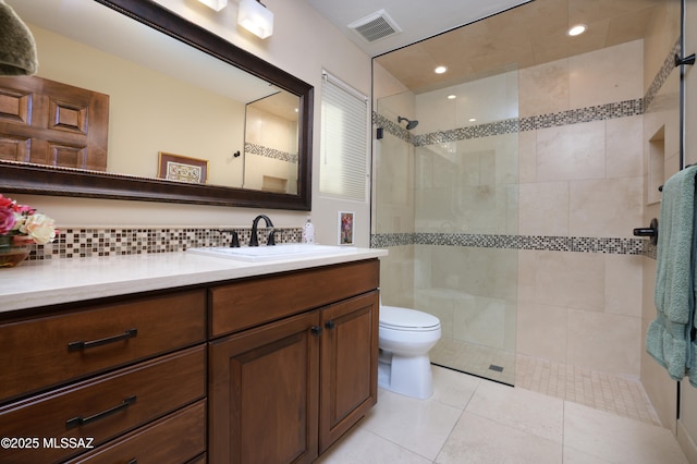 bathroom featuring tile patterned flooring, toilet, tiled shower, vanity, and backsplash