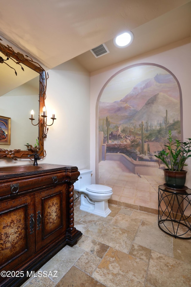 bathroom with toilet, an inviting chandelier, and vanity