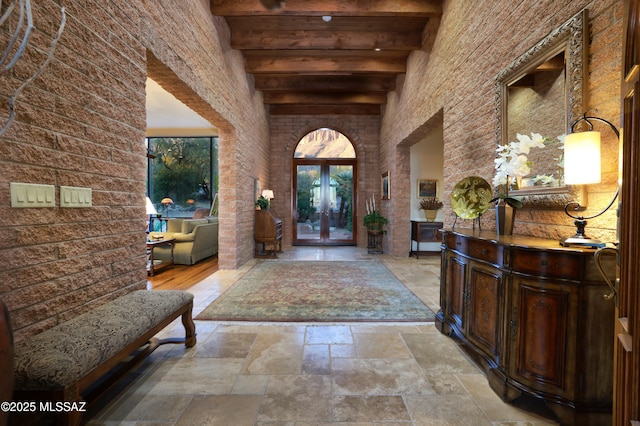 foyer with a towering ceiling, french doors, and beamed ceiling