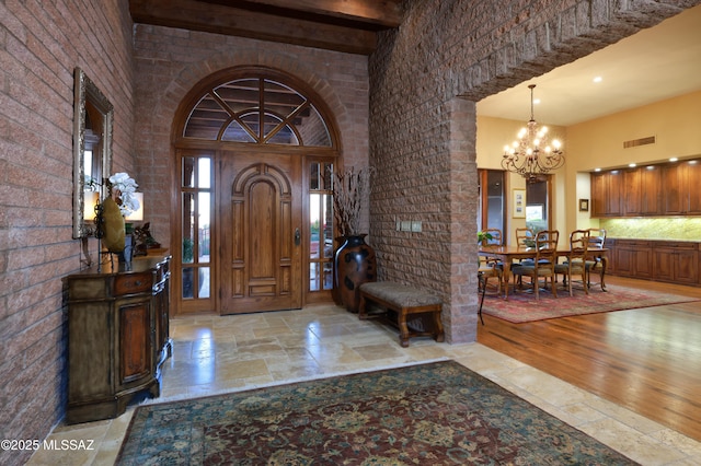 entryway with a high ceiling, a chandelier, and light hardwood / wood-style floors