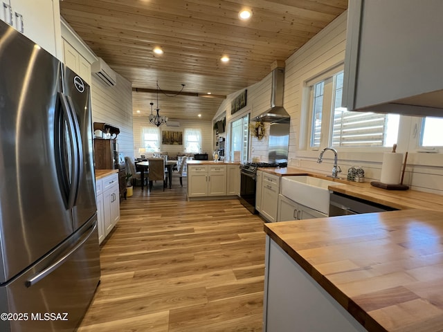 16911 S Joshua Tree Rd, Mayer, AZ 86333 - kitchen with stainless steel appliances, butcher block countertops, wall chimney range hood, wood ceiling, and healthy amount of natural light