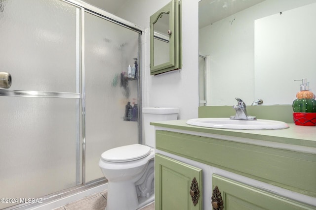 bathroom with tile patterned flooring, vanity, toilet, and walk in shower