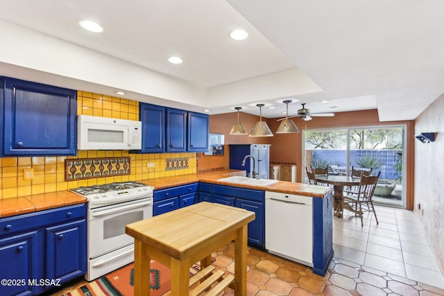 kitchen featuring kitchen peninsula, white appliances, blue cabinets, sink, and pendant lighting