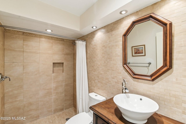 bathroom with walk in shower, vanity, toilet, and tile walls