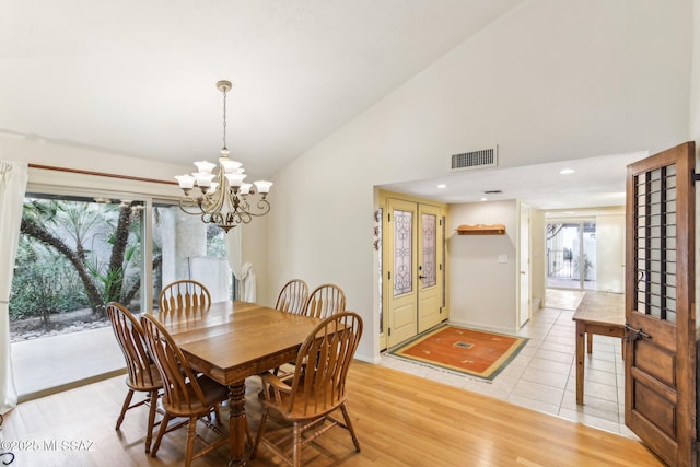 dining space with light hardwood / wood-style floors, vaulted ceiling, and a notable chandelier