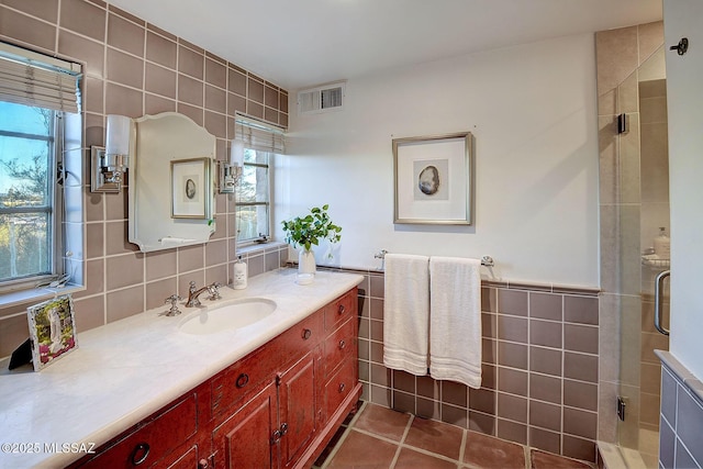 bathroom with vanity, an enclosed shower, tile patterned floors, and tile walls