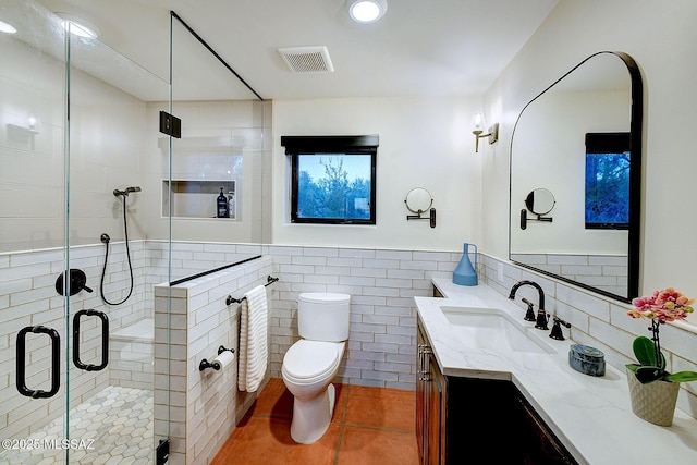 bathroom with toilet, an enclosed shower, tile walls, tile patterned floors, and vanity