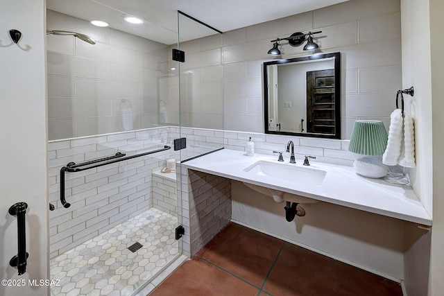 bathroom featuring a shower with shower door, sink, tile walls, and tile patterned flooring