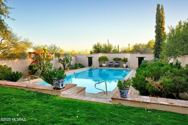 pool at dusk featuring a lawn