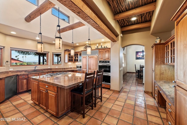 kitchen with a kitchen breakfast bar, stainless steel appliances, beamed ceiling, a center island, and hanging light fixtures